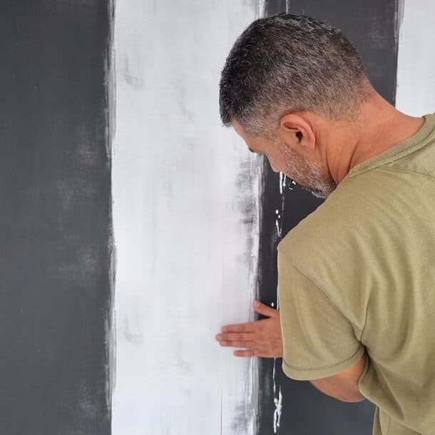 Home Collections person installing wallpaper on a wall