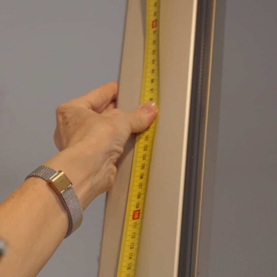 person holding a measuring tape against a window
