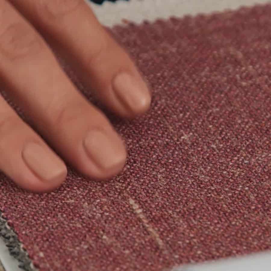 A hand touching a piece of textured fabric sample