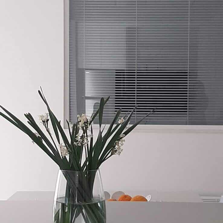Venetian aluminium white blind, 25mm wide, installed on indoor glass partition