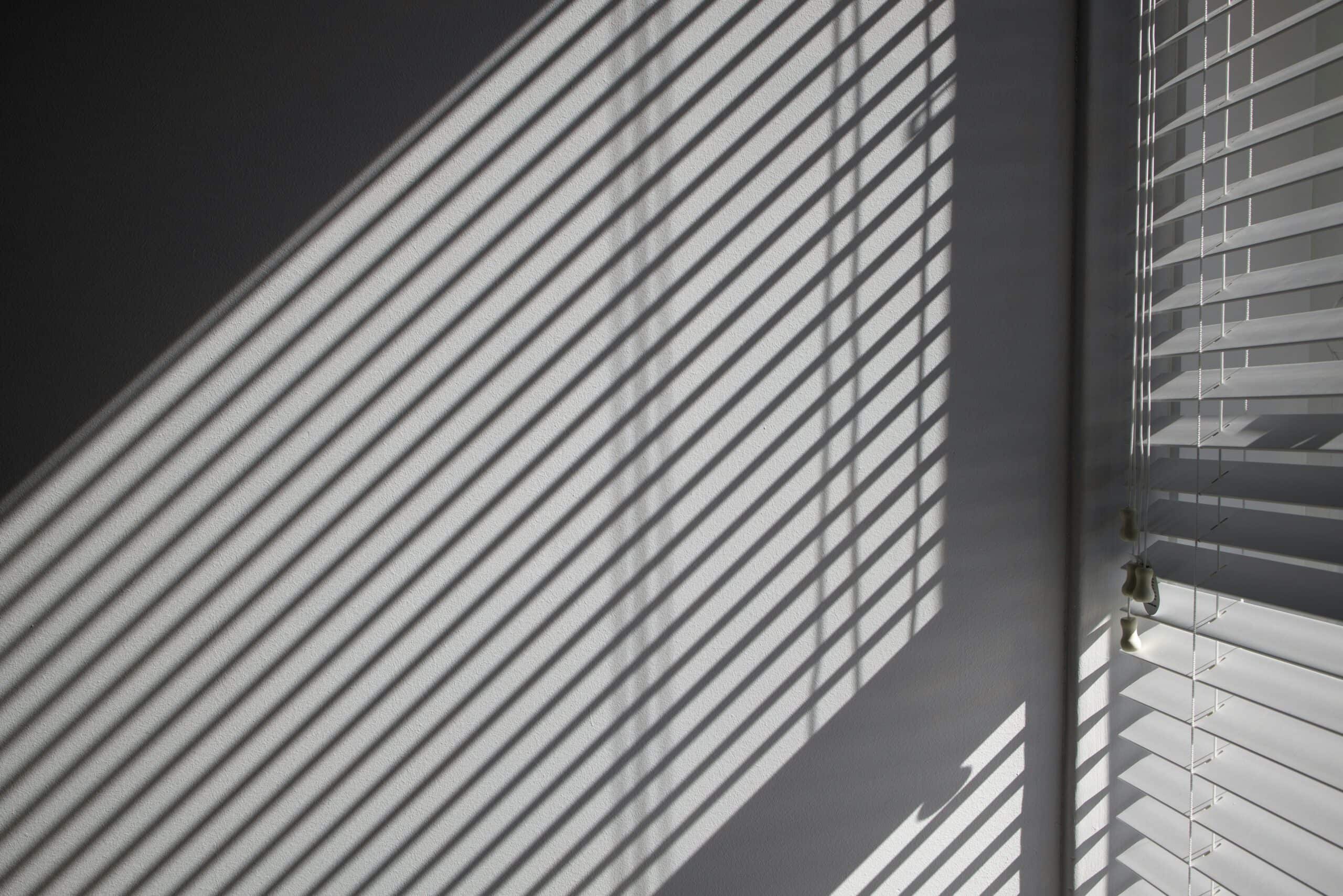 Venetian blinds casting shadows on a wall